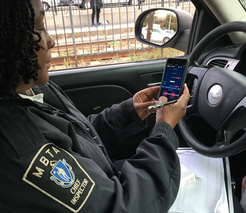 A chief inspector on the MBTA Green Line looking at a train app on her phone while sitting in the car.